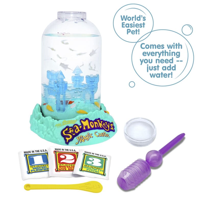 23230-Sea-Monkeys Magic Castle-Image2 Three packets, numbered 1, 2, and 3 from left to right are vivble in front of the Magic Castle aquarium. There is a small yellow Sea-Monkeys spoon laying in front of the packets, and a purple pipette and clear circle magnifyer next to the spoon. There are two callouts in circles. They read "World's Easiest Pet!", and "Comes with everything you need -- just add water!"